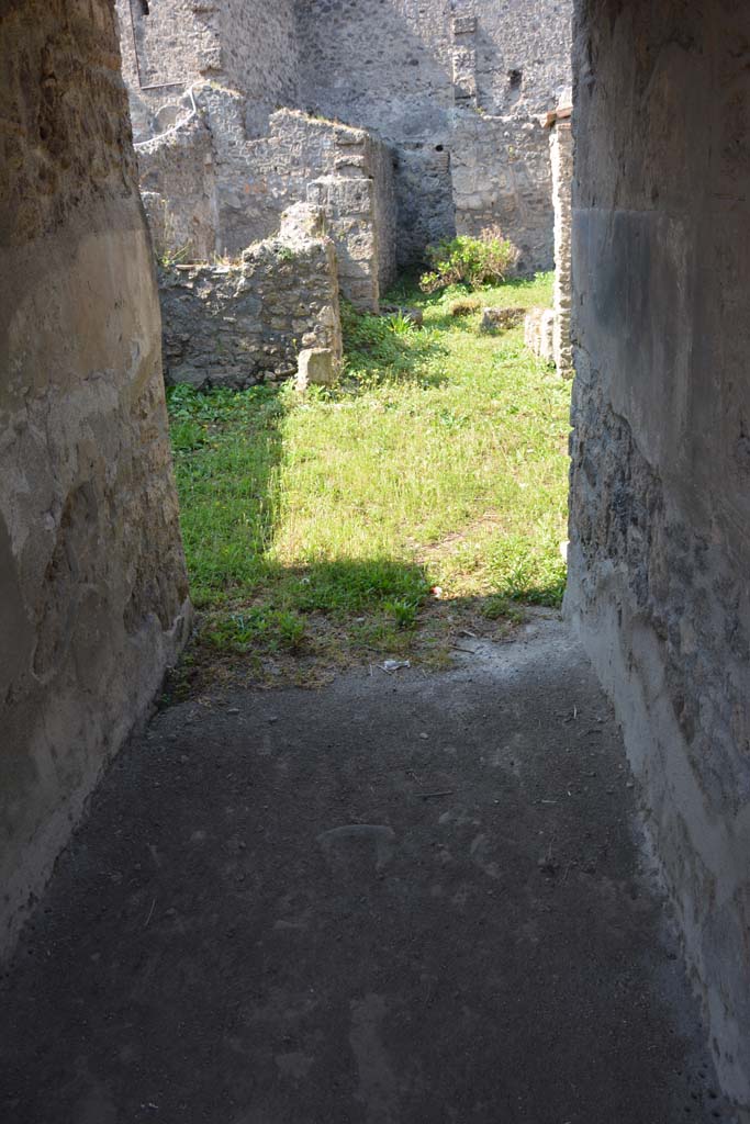 I.10.18 Pompeii. April 2017. Looking west from entrance corridor/fauces.
Photo courtesy Adrian Hielscher.
The entrance doorway enters through the spacious entrance corridor with rustic flooring and walls covered with fine black plaster, into a small tuscanic atrium. Opening, on either side of the entrance corridor, were rooms 2 and 3, both with door-jambs painted in red, both lit by a rectangular window which opened in the east wall overlooking the roadway. 
The room to the left of the fauces/corridor (room 2), probably a cubiculum, was decorated with a low light red zoccolo topped with a narrow red band edged by white lines and decorated with white geometric patterns. The upper area of the wall was simple white rough plaster. 
The room to the right (room 3) was an oecus, it was decorated with a high pink zoccolo, above which the part of the wall had been left of rustic white plaster, equally rustic was the flooring.
See Notizie degli Scavi, 1934, (p.341-4)




