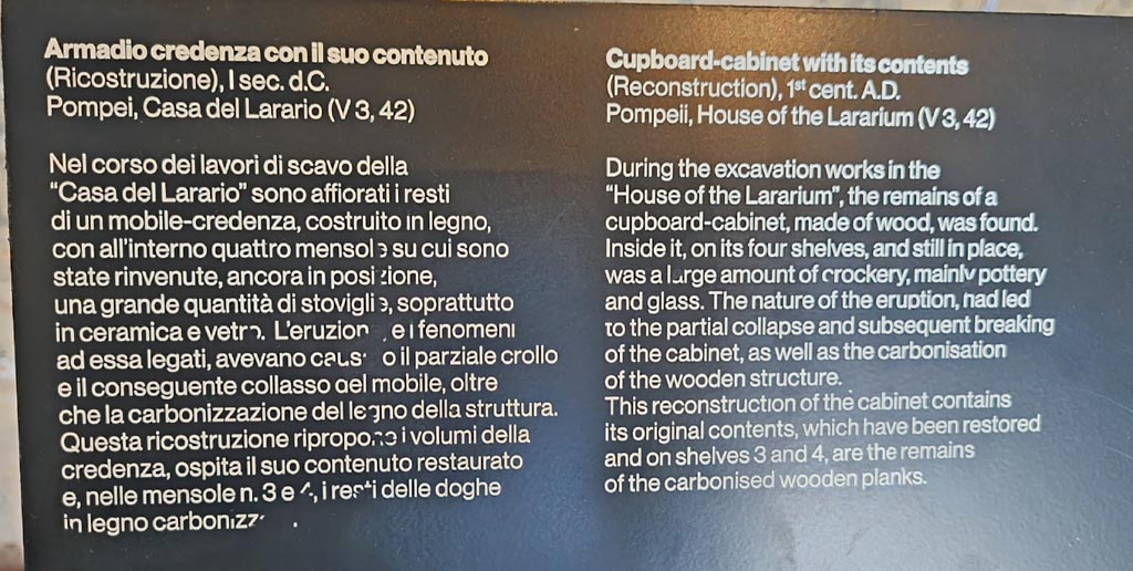 V.3.13 Pompeii. March 2024. Description card for cabinet and its contents in exhibition entitled –
“L’altra Pompei, vite comuni all’ombra del Vesuvio”. Photo courtesy of Giuseppe Ciaramella.

