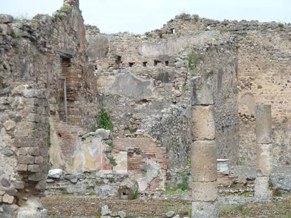 VII.13.4 Pompeii. May 2010. North-west corner of peristyle with painted plaster, and rear triclinium room of VII.13.21.
According to Boyce, on the west wall of the peristyle was a rectangular niche (h.0.40, w.0.36, d.0.20, h. above floor 1.60). 
Originally this appeared to have been fitted with an aedicula façade but now gone. 
The interior walls were coated with white stucco and had delicate decorations in relief. 
These included a cornice which ran around the top of the three walls.
See Boyce G. K., 1937. Corpus of the Lararia of Pompeii. Rome: MAAR 14. (p.71 no.323)

