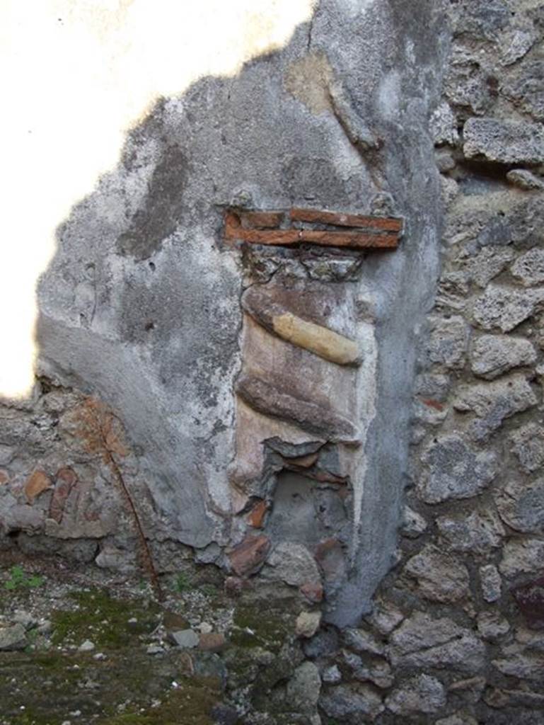 VII.15.13 Pompeii. December 2007. Lararium in kitchen area. 
According to Boyce, in the kitchen, located on the east side of the entrance fauces on the east wall above the hearth, was the lararium.
An altar in the form of a low half-column of stucco was applied to the wall and painted red.
Around it coiled a serpent in yellow stucco relief, half of its body in elaborate rings above and to the right of the altar, and actually tied into a knot.
Above the top of the altar “the usual fruits” were reported to have been painted.
On each side was the figure of a Lar.
Below and to the right is painted a tabella ansata, as if meant to contain an inscription, though none was visible at the time of excavation.
The whole painting was bordered by red stripes, and across the top were stretched three garlands.
See Boyce G. K., 1937. Corpus of the Lararia of Pompeii. Rome: MAAR 14, (p.73, no.335, and Pl.23,2). He located this at VII.15.12.
See Giacobello, F., 2008. Larari Pompeiani: Iconografia e culto dei Lari in ambito domestico. Milano: LED Edizioni, (p.195, no.82).

