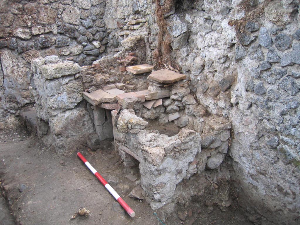 VIII.7.10 Pompeii. August 2005. Looking south-east in kitchen area towards hearth at east end of south wall.
The remains of the lararium niche may be partly visible on the upper right of centre of the photo.
Photo courtesy of Pompeii Archaeological Research Project: Porta Stabia.
According to Mau -
“Next to the hearth there was the usual painting of the Lares, and a niche.”
See Mau in BdI, 1875, (p.167) (p.166-169 - La quarta casa). 

