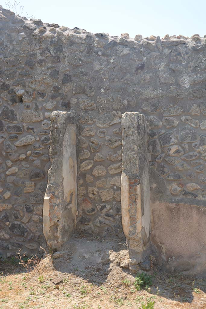 IX.2.27 Pompeii. July 2017. Looking towards west wall of peristyle, with remains of shrine. 
Foto Annette Haug, ERC Grant 681269 DÉCOR.
According to Boyce, -
Above a low podium (1.10 by 0.70, h.0.40) two enclosing walls (h. as far as preserved 1.30) built against the wall of the room form a rectangular niche (w.0.60, d.0.50) above a low podium, but none of the floor was preserved. 
The inside walls are painted blue with red borders. 
On the ground in front of the shrine stood a square masonry altar.
See Boyce G. K., 1937. Corpus of the Lararia of Pompeii. Rome: MAAR 14. (p. 82, no. 405)
Giacobello described this as an Aedicula lararium. 
See Giacobello, F., 2008. Larari Pompeiani: Iconografia e culto dei Lari in ambito domestico. Milano: LED Edizioni, (p.284 no.V77)


