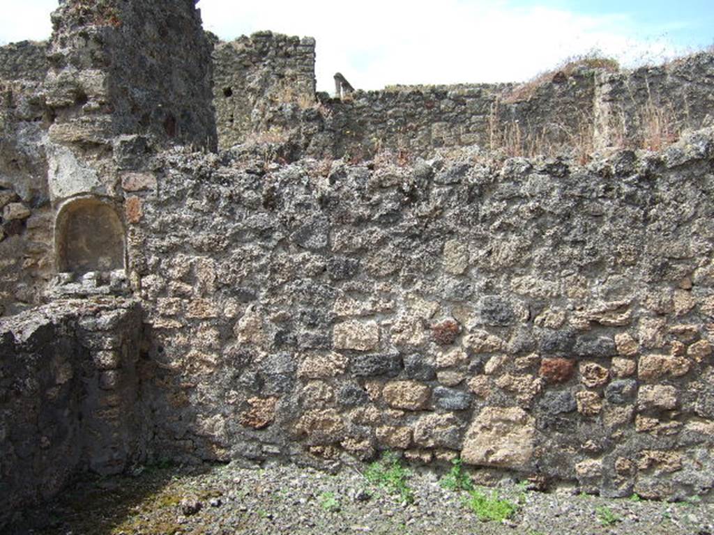 IX.9.6 Pompeii.  May 2006. West wall of wide portico, with lararium niche.
This portico was supported by two pillars, by a masonry arch and a long architrave.
The portico had rustic walls with a high black zoccolo/plinth, which, however, was not continuous: in the west wall, and really in the vertical wall from which the arch originated, a semicircular niche covered in white plaster was hollowed out. Underneath of which, was a matching masonry altar, leaning against the wall and parapet of the inter-columnisation.
See Notizie degli Scavi di Antichità, 1889, p.123.

