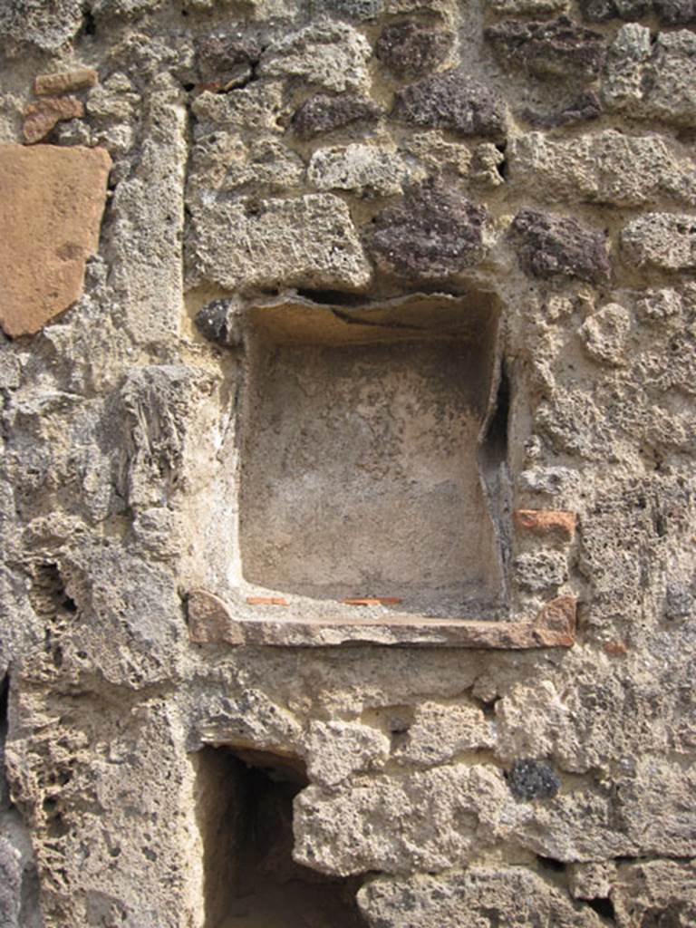 I.3.8a Pompeii. September 2010. Detail of niche on east wall. Photo courtesy of Drew Baker.
According to Boyce, this rectangular niche was to be found in the east wall of the kitchen, above the hearth.
Its walls were coated with successive layers of plaster.
See Boyce G. K., 1937. Corpus of the Lararia of Pompeii. Rome: MAAR 14. (p.24, no.21) 

