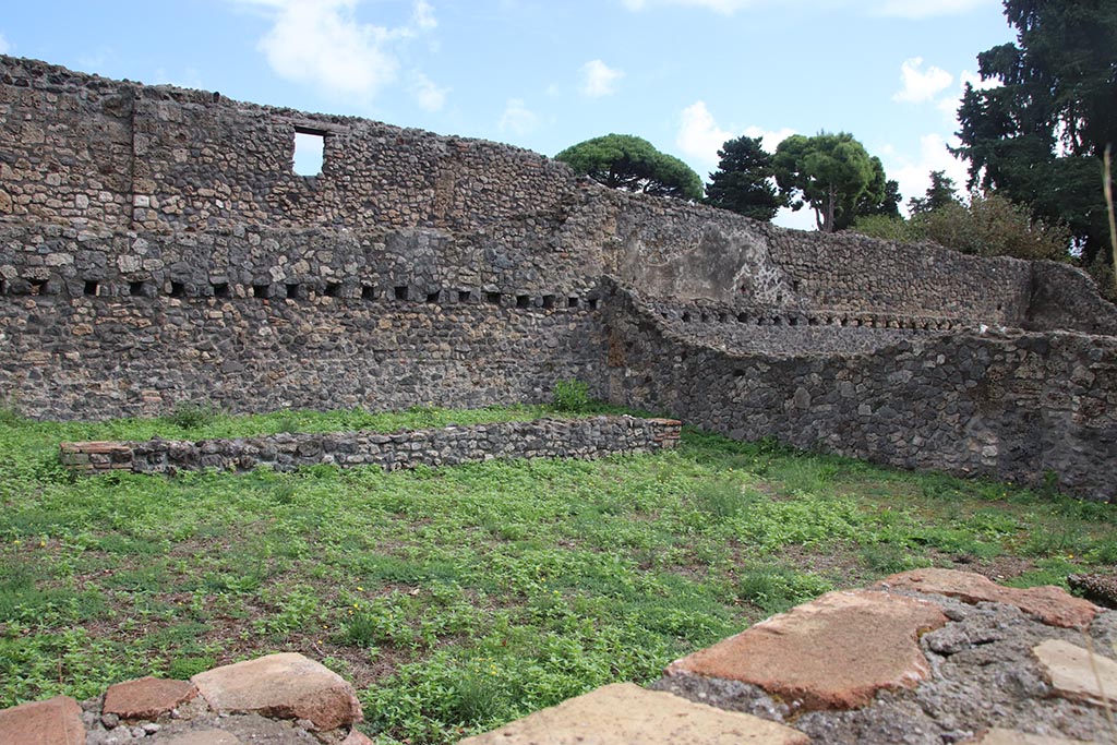 I.1.8 Pompeii. October 2024. Looking south-east across yard, towards the stables area, at rear of small wall. Photo courtesy of Klaus Heese.