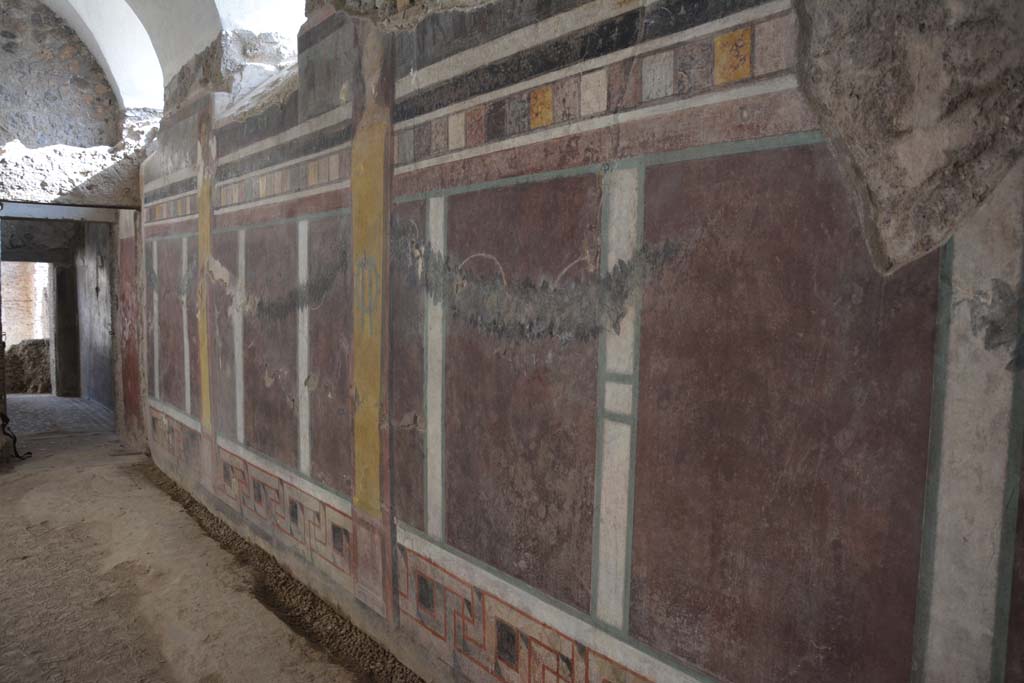 I.6.2 Pompeii. September 2019. Looking south along west wall of east wing of cryptoporticus.
The base of the wall has a meander pattern.
Above this are geometric patterns with garlands and yellow herms each with a portrait head at their top.
On the upper part of the wall a number of scenes are painted.
Foto Annette Haug, ERC Grant 681269 DÉCOR.

