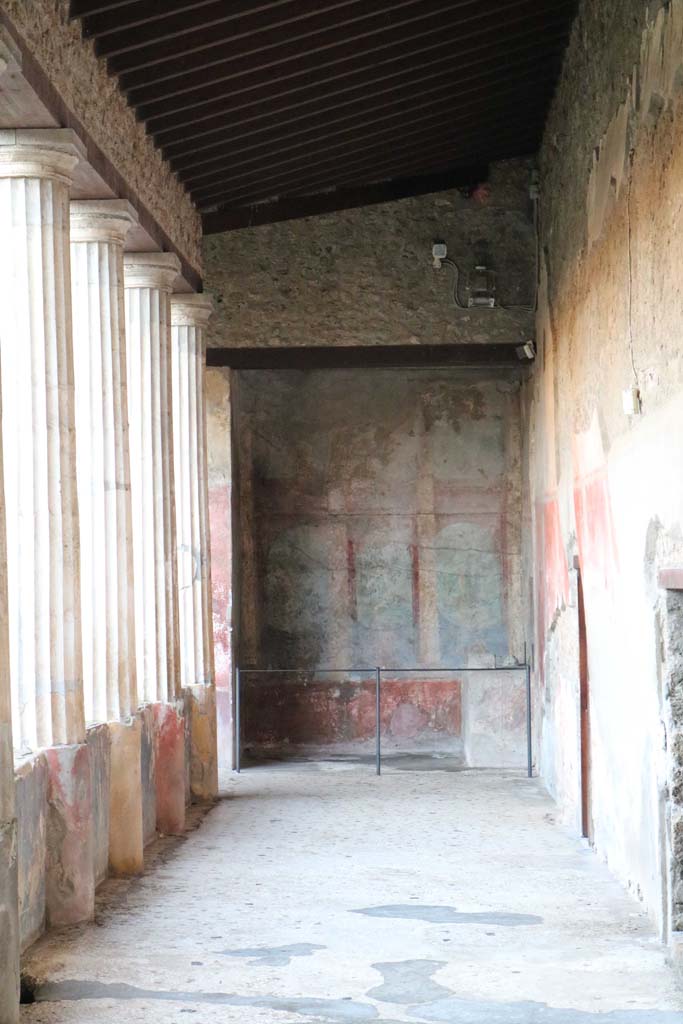I.10.4 Pompeii, December 2018. 
Looking south along west portico to Sacrarium with built in altar and apsed niche. 
The walls have painted columns and pilasters opening onto a painted garden with trees and birds.
Photo courtesy of Aude Durand.
