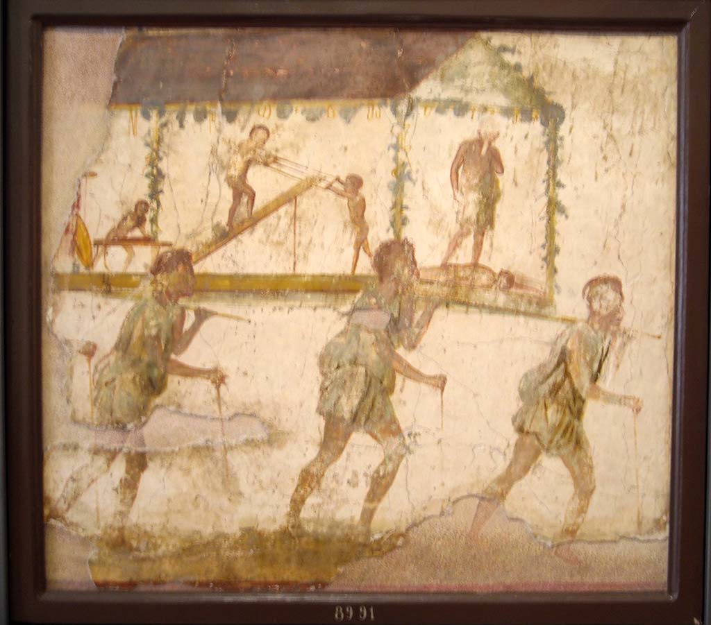 VI.7.9 Pompeii. Wall painting of the Procession of the Carpenters.   
Originally found on pilaster between entrances VI.7.8 and VI.7.9.
Now in Naples Archaeological Museum. Inventory number 8991.
See Helbig, W., 1868. Wandgemälde der vom Vesuv verschütteten Städte Campaniens. Leipzig: Breitkopf und Härtel. (1480).
According to Leach, figures of Minerva, Mercury and Daedalus painted on its exterior pilasters (6.7.8-12), as well as another painting of a procession advertising the craft of Daedalus under the protection of Minerva and Mercury, were taken by Mau as an indication that this was a Carpenter’s workshop.
The sign showed 3 carpenters bearing a ferculum (bier or litter) that included a figure of Daedalus and some workmen performing carpenters’ tasks.  
A dead figure lies before Daedalus' feet: this may well be a reference to the nephew Perdix whom the legendary artisan murdered through jealousy for his invention of the rake.  
(PPM 4, p389-91, however, suggested that the sign indicated a perfumer’s shop that dealt in spices requisite to funeral rituals).
See Leach, E.W: The Social Life of Painting in Ancient Rome and on the Bay of Naples.

