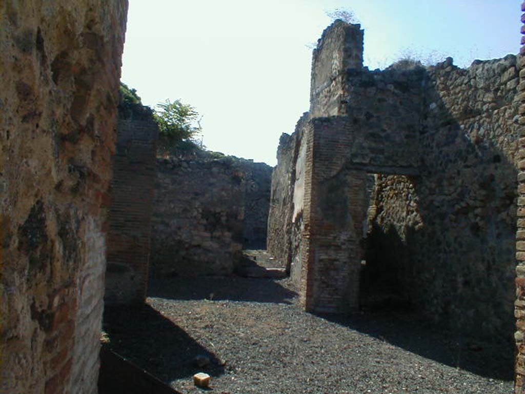 VI.14.30 Pompeii. September 2004. 
Looking west across atrium towards tablinum with doorway to corridor linking to VI.14.32 in its west wall.
On the right would have been the doorway to the beginning of the stairs that led to a room above the tablinum.
According to BdI, the flooring of both the fauces and atrium were of a type of opus Signinum.
In this case, lines of white stones were used instead of crushed brick.
The impluvium of the Tuscanic atrium was faced with real opus Signinum.
The place of the tablinum was occupied by a room that was not open onto the atrium in its usual entire width.
The tablinum was entered by two doors from the atrium, the largest on the right side.
A third doorway in the south (left) side of the tablinum led into the small garden area. 
A fourth doorway was in the west wall of the tablinum.
Also found on the west wall were fragments of the dado.
See Bullettino dell’Instituto di Corrispondenza Archeologica (DAIR), 1876, (p.52-3)
