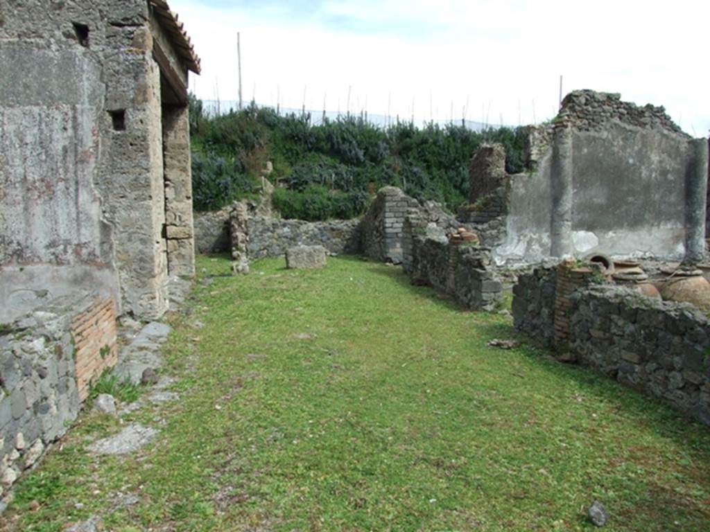 VI.16.27 Pompeii. March 2009. Looking east across north portico.
According to Jashemski, the peristyle garden had a wide portico on the north.  The portico was supported by three columns and one engaged column, covered with rough plaster, red at the bottom.  They were connected by a low masonry wall with an entrance into the garden between the first and second columns, from the east.  Numerous dolia and large jars were found embedded in the soil in the north-east corner of the garden.  See Jashemski, W. F., 1993. The Gardens of Pompeii, Volume II: Appendices. New York: Caratzas. (p.164)
