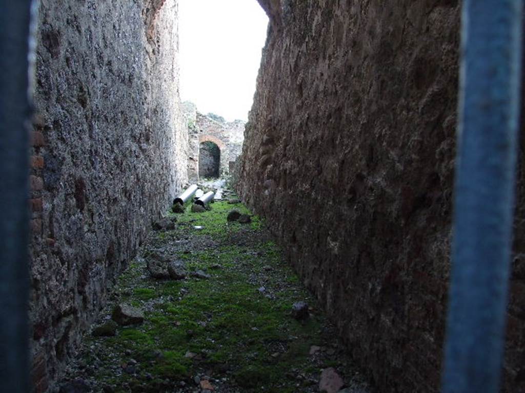 VII.1.8 Pompeii . December 2006. Corridor running south along rear of VII.1.52 to VII.1.58 on right. On the left is the rear wall of the baths, nymphaeum G, pool D and nymphaeum F. Underneath is an underground corridor running from rooms T and U to an underground storeroom V. This is an irregular shaped room carved into the stone below the pool D. Originally it was probably a tomb dating back to 6th or 7th century B.C.