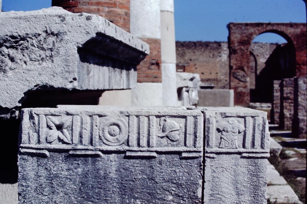 VII.8 Pompeii Forum. 1968. 
Looking north at south side. Statue base decorated with flower, shield, helmet and armour motifs. Photo by Stanley A. Jashemski.
Source: The Wilhelmina and Stanley A. Jashemski archive in the University of Maryland Library, Special Collections (See collection page) and made available under the Creative Commons Attribution-Non-Commercial License v.4. See Licence and use details.
J68f0989
