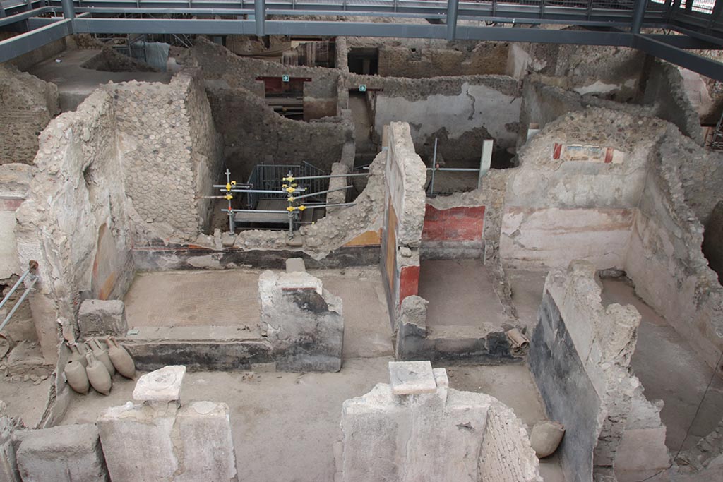 IX.12.4 Pompeii. October 2024.
Looking east towards room “o”, on left, room “l(L)” with red painted walls, centre right, and room “f”, on its south side, on right.
On the upper east wall of room “f”, the painting described as from the zoccolo of an upper room, can be seen.
Photo courtesy of Klaus Heese.
