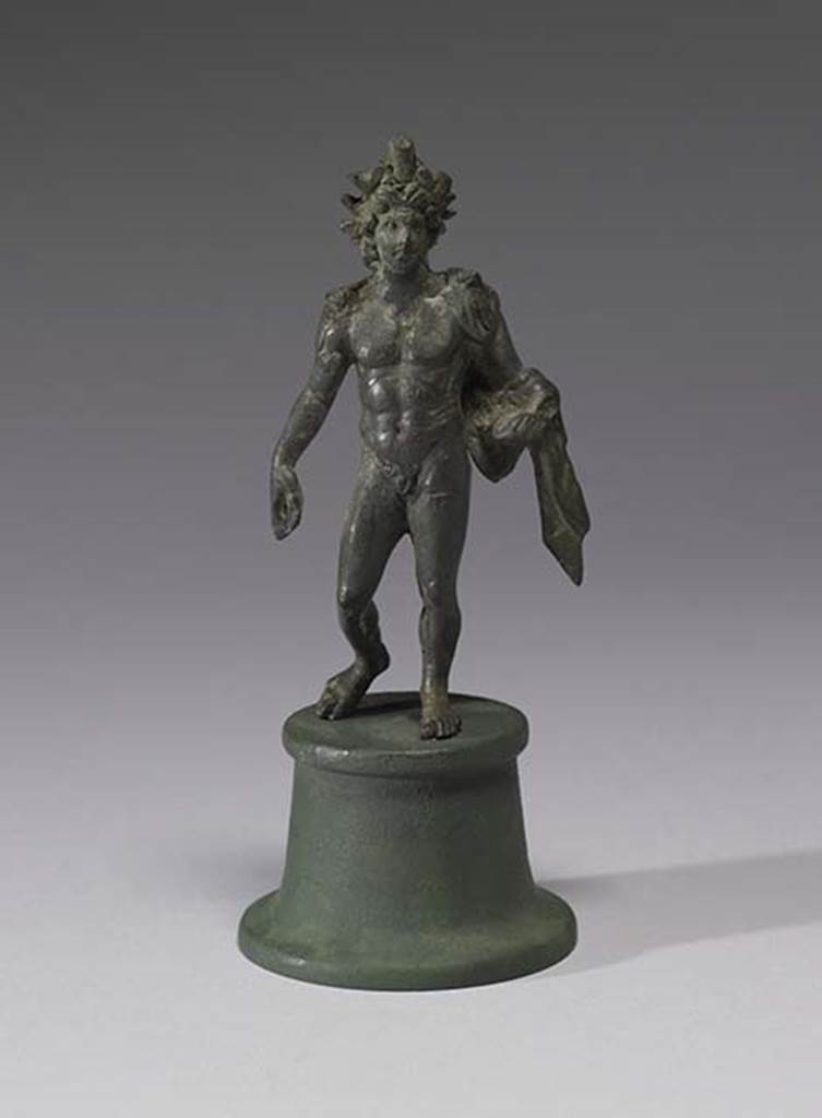 Boscoreale, Villa rustica in fondo DAcunzo. Room 12, lararium. 
Bronze statuette of Alexander Helios, 0.13m high, front view.
A beautiful smiling Helios, he is portrayed nude, with a radiate crown upon his head. 
He wears a light veil falling from his shoulders and wrapping around his left forearm.
The left hand (with globe) was missing. 
A lorum (leather strap or thong) would have perhaps been the attribute carried downwards in the right hand.  
Photo courtesy of The Walters Art Museum, Baltimore. Inventory number 54.2290.
http://thewalters.org/
Creative Commons Attribution-ShareAlike 3.0 Unported Licence
