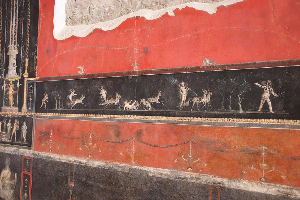 VI.15.1 Pompeii. October 2024. 
Centre of east wall with painted panel of cupids in a race between chariots pulled by deer. Photo courtesy of Klaus Heese.
