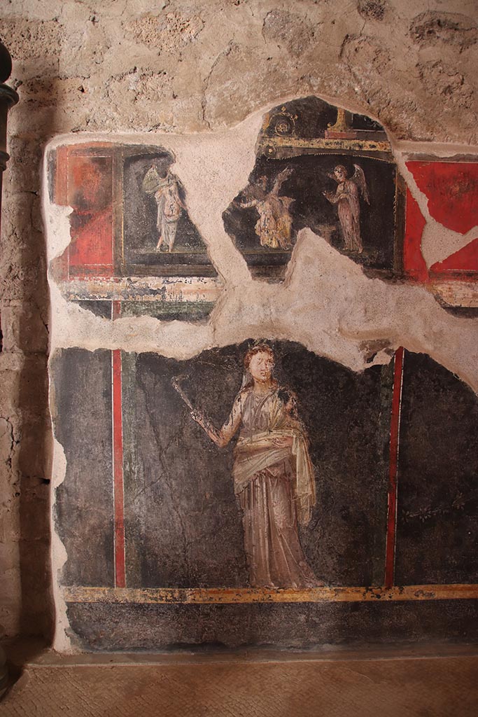 VI.15.1 Pompeii. October 2024. 
West wall at south end. The wall painting above is of three Psychai gathering flowers.
Below is a female figure or priestess holding implements of sacrifice.
Photo courtesy of Klaus Heese.
