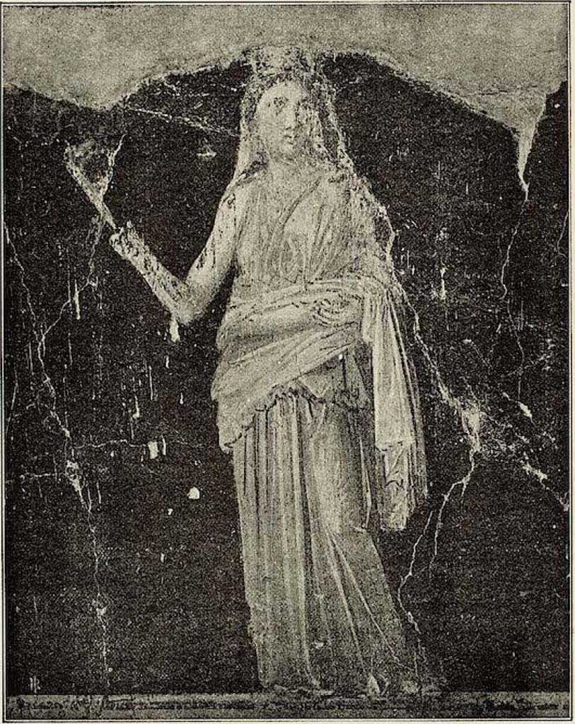 VI.15.1 Pompeii. Painted panel on zoccolo (0.50 high) from west wall at south end.
Described by Sogliano as –
“Figura muliebre, coronata di foglie e con un velo che le discende dall’occipite sulle spalle: indossando una veste paonazzo-chiaro, con manto giallognolo, tiene nella dritta una fiaccola, e con la sinistra sostiene, intorno ai lombi, una piega del manto.”
(A feminine figure crowned with leaves and with a veil descending from her head onto her shoulders: wearing a pale-purple robe, with a yellowish mantle, she holds a torch in her right hand, and with her left hand supports, around her waist, a fold of the mantle.) 
See Sogliano, A. La Casa dei Vettii in Pompei Mon. Ant. 1898. (p.369-370, fig. 61).
