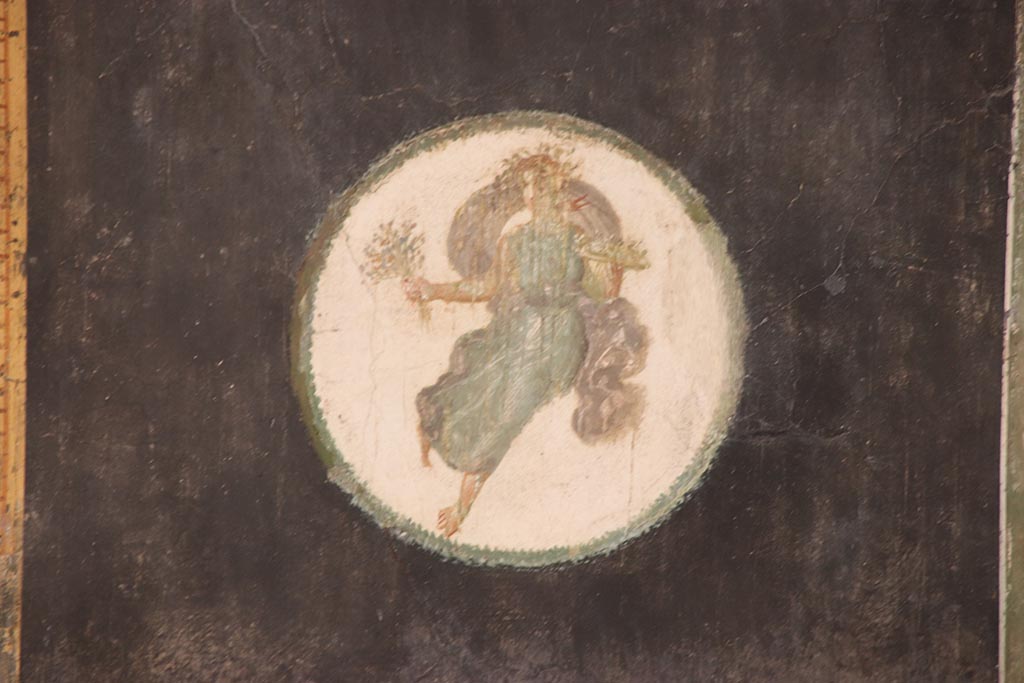 VI.15.1 Pompeii. October 2024.
Triclinium “t”, detail of painted figure in medallion at the south end of the east wall. Photo courtesy of Klaus Heese.
