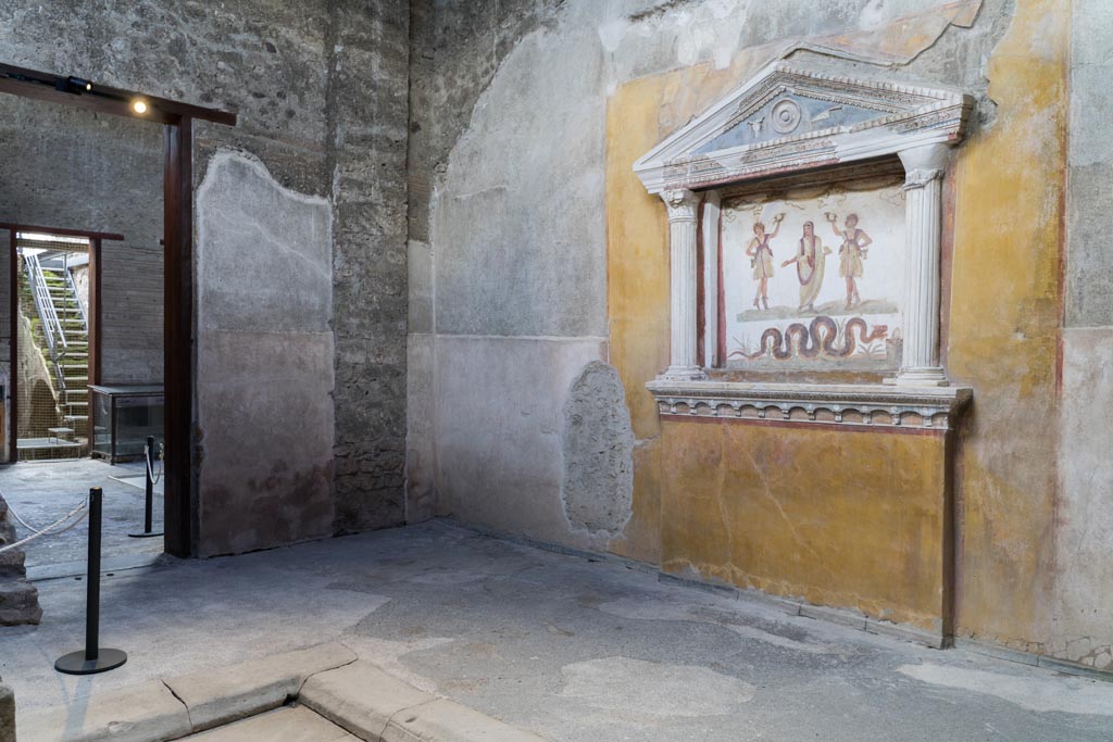 VI.15.1 Pompeii. March 2023. 
Looking across impluvium in services area towards lararium on west wall, and doorway to atrium in south wall.
Photo courtesy of Johannes Eber.
